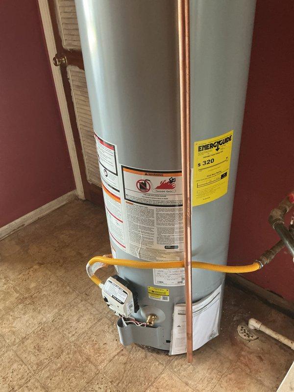 Completed installation of 40-gallon gas slim water heater in residential utility closet. Connected copper water supply lines with brass shut-off valves, attached flexible yellow gas line to unit, and verified proper venting through existing galvanized vent pipe extending through ceiling. Installation includes 6-year manufacturer warranty on parts and 1-year labor warranty.