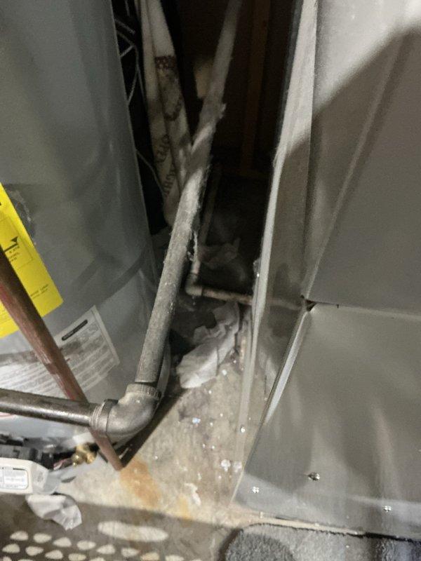 Completed comprehensive HVAC replacement estimate for residential forced-air heating system located in basement utility area. Existing furnace unit evaluated and documented, showing signs of moisture accumulation in drain pan and water staining on concrete floor surrounding equipment base. Assessment included inspection of flexible ductwork distribution system, condensate drainage components with PVC piping, and overall equipment condition with visible wear patterns consistent with aging system operation.