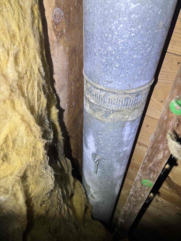 Responded to a no cooling complaint on a 4-year-old system where the back bedroom had no airflow and the rest of the home was warmer than normal. Upon inspection, discovered severe condensation and frost accumulation on supply ductwork in the attic space, indicating inadequate insulation on the duct and possible airflow restriction. The heavy moisture buildup on the metal duct surface was causing reduced air delivery to the affected bedroom zone. Documented the compromised duct insulation showing water staining and compression, as well as the extent of condensation on the uninsulated duct sections. Advised that the ductwork requires proper insulation wrap to prevent condensation issues and restore adequate airflow to all zones.