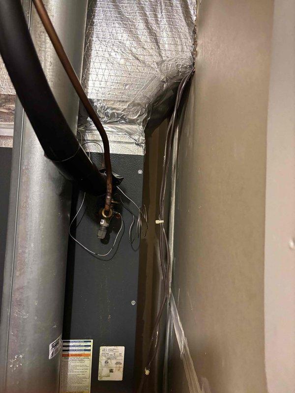 Responded to no cooling complaint on 7-year-old residential HVAC system. Upon arrival, confirmed adequate airflow from supply vents with no ice buildup present at indoor unit. System was actively running but delivering warm air to conditioned space. Performed visual inspection of air handler and associated refrigerant lines in utility closet. Investigated reported fluid leak concern around equipment area. Examined copper refrigerant lines, insulated suction line, and air handler cabinet for signs of refrigerant oil migration or other fluid discharge. Documented system installation configuration including ductwork connections and electrical components for diagnostic reference.