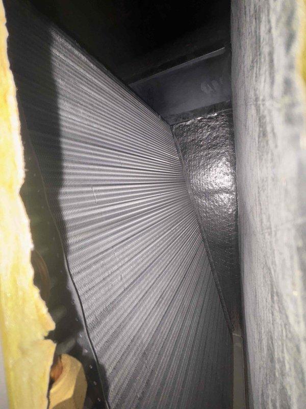Completed follow-up visit to address outstanding HVAC installation items. Inspected and documented ductwork system including flexible metallic ducting, foil-backed vapor barrier, and fiberglass insulation in confined air handling space. Verified proper installation of furnace unit, condensate drainage system with PVC piping and safety valves, condensate pump with yellow discharge line, and refrigerant lines with reflective insulation wrapping to ensure all components meet code requirements and manufacturer specifications.