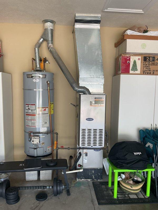 Conducted comprehensive replacement estimate for existing HVAC system at residential property. Evaluated current Carrier furnace unit located in garage alongside water heater, assessing ductwork connections, ventilation routing, and existing infrastructure. Inspected outdoor condenser unit positioned on concrete pad against brick exterior wall, noting electrical disconnect configuration and overall system condition. Documented equipment specifications, spatial constraints for new installation, and provided homeowner with replacement options for complete heating and cooling system upgrade.