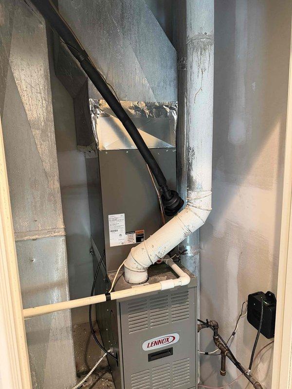 Completed installation of a 2.5-ton, 15.5 SEER air conditioning system with matching evaporator coil in an upflow configuration. The outdoor condenser unit was positioned on a concrete pad against the exterior wall with proper electrical disconnect and control wiring installed, while the indoor evaporator coil was integrated with the existing Lennox furnace system in the basement utility area with all refrigerant lines, condensate drainage, and ductwork connections properly completed and tested.