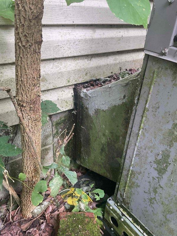 Conducted comprehensive HVAC system evaluation for heating and cooling replacement estimate on a packaged unit installation serving a 1001-1599 square foot residential structure utilizing natural gas energy source. Assessed existing exterior-mounted packaged unit positioned on deteriorated concrete pad with significant algae and moss accumulation, noted inadequate clearances due to vegetation encroachment, and documented weathered electrical disconnect, compromised refrigerant line insulation, and deteriorating foundation access panel with organic growth. Provided detailed photographic documentation of current equipment condition, installation deficiencies, and site constraints to develop accurate replacement specifications for new packaged HVAC system.