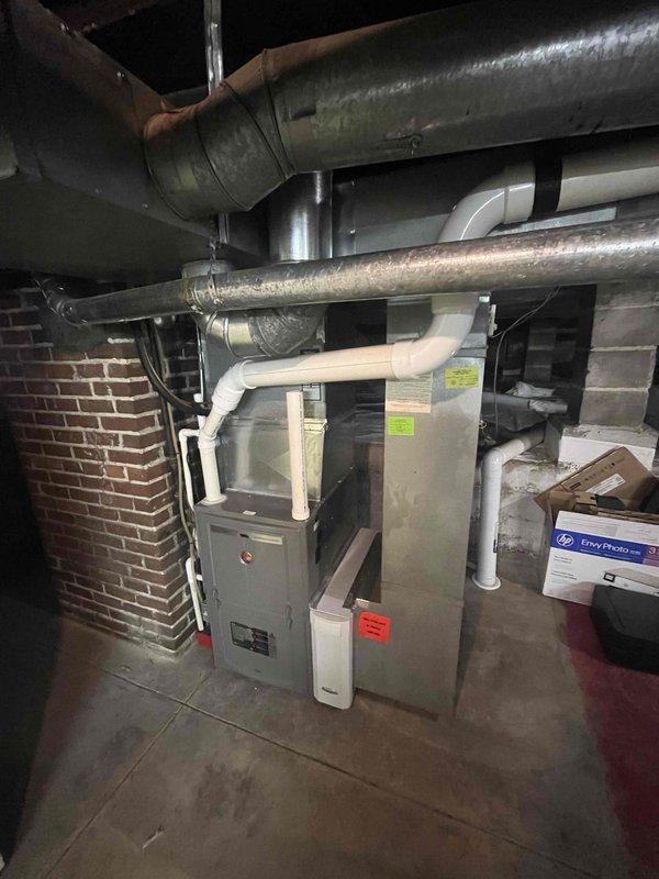 Conducted comprehensive assessment of existing HVAC system in basement installation for equipment replacement estimate. Customer reported current system operational but seeking replacement options. Evaluated gray metal furnace unit with associated ductwork, PVC condensate drainage system, and electrical disconnect box. Documented existing configuration including galvanized steel ductwork with horizontal ceiling runs, vertical air handler placement, and mechanical room layout adjacent to exposed brick wall. Photographed equipment specifications, manufacturer labels, and current installation conditions to provide accurate replacement recommendations and ensure proper sizing for new system installation.