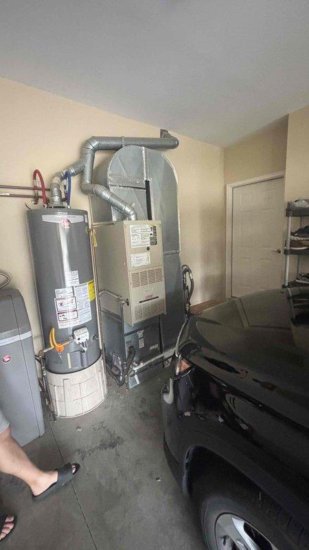 Conducted comprehensive assessment of 23-year-old non-operational main level HVAC system in residential property with two separate systems. Documented existing gray metal furnace unit with flexible ductwork configuration, thermostat wiring setup including red, yellow, blue, green, and white conductor connections, and overall equipment layout in utility room shared with water heater and filtration equipment. Prepared replacement estimate with A+ priority classification for failed main level heating and cooling system.