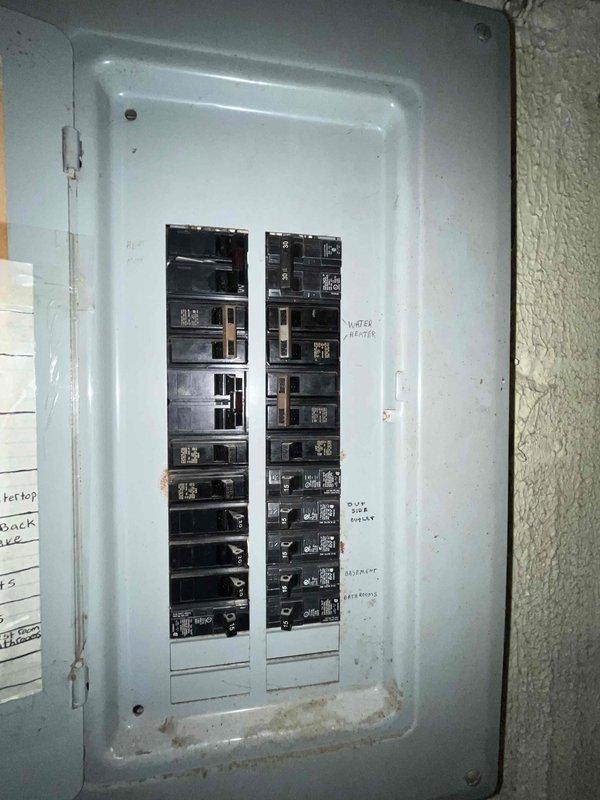 Conducted comprehensive site assessment for complete HVAC system replacement involving both heating and cooling equipment. Evaluated existing electrical infrastructure and condensate drainage system, documenting current panel configuration with circuit breaker arrangement and existing drain pan condition showing mineral deposits and water staining, indicating need for complete system removal and installation of new equipment with updated safety components including proper float switch integration.