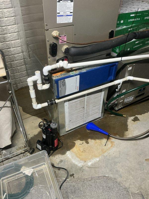 Responded to water leak emergency at basement geothermal HVAC system approximately 15 years old. Upon arrival, found significant water accumulation across concrete basement floor originating from condensate drainage system. Inspected air handler unit, PVC condensate piping configuration, and black condensate pump assembly for source of failure. Diagnosed failed condensate pump as primary cause of water overflow. Replaced malfunctioning condensate pump with new unit, reconnected discharge piping, and verified proper drainage function through multiple test cycles. Cleared standing water from basement floor area surrounding equipment. Confirmed all connections sealed properly with no active leaks present. System tested and returned to normal operation with condensate properly evacuating through drainage system.