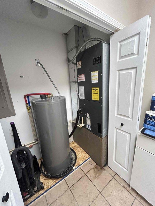 Responded to no-cool service call on single-story residential property where system had frozen evaporator coil. Upon arrival, found air handler in interior closet with ice buildup that had been previously identified by handyman, unit was already shut down per recommendation to allow defrosting. Inspected Robertshaw thermostat showing 77.2°F reading, verified system was off and assessed HVAC equipment located in utility closet alongside water heater. Documented existing conditions with photos showing air handler unit with visible manufacturer labels and connected ductwork, confirmed active water leakage from melting ice with no structural damage reported at time of service.