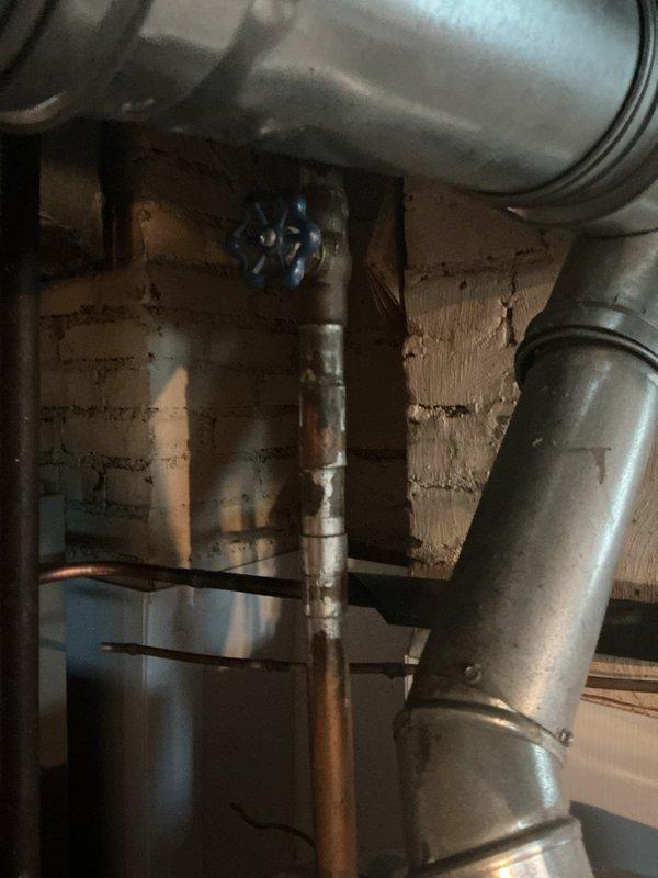 # Water Heater Maintenance Service

Performed comprehensive tanked water heater flush on A.O. Smith residential unit located in basement utility area. Conducted complete system drainage to remove sediment buildup and mineral deposits from tank interior, which improves heating efficiency and extends equipment lifespan. 

Connected garden hose to drain valve at base of unit and opened valve to flush accumulated sediment from tank bottom. Allowed water to run until discharge was clear, indicating thorough removal of debris. Inspected cold water supply line with blue-handled shut-off valve for proper operation and verified all copper piping connections at top of unit for signs of corrosion or leaks.

Examined temperature and pressure relief valve for proper function and checked that discharge tube was properly positioned. Verified all manufacturer labels and specifications remained legible on unit exterior. Inspected surrounding plumbing infrastructure including exposed copper lines and ga