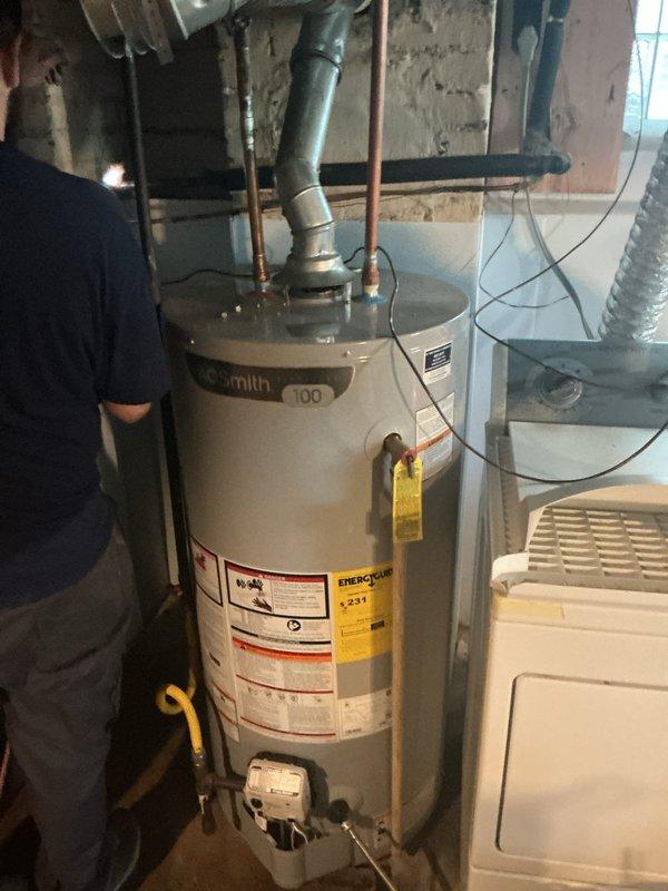 # Water Heater Maintenance Service

Performed comprehensive tanked water heater flush on A.O. Smith residential unit located in basement utility area. Conducted complete system drainage to remove sediment buildup and mineral deposits from tank interior, which improves heating efficiency and extends equipment lifespan. 

Connected garden hose to drain valve at base of unit and opened valve to flush accumulated sediment from tank bottom. Allowed water to run until discharge was clear, indicating thorough removal of debris. Inspected cold water supply line with blue-handled shut-off valve for proper operation and verified all copper piping connections at top of unit for signs of corrosion or leaks.

Examined temperature and pressure relief valve for proper function and checked that discharge tube was properly positioned. Verified all manufacturer labels and specifications remained legible on unit exterior. Inspected surrounding plumbing infrastructure including exposed copper lines and ga