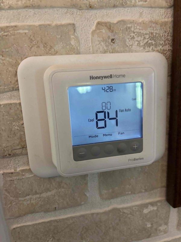 Responded to no-cooling complaint on 6-year-old residential air conditioning system with indoor temperature exceeding 90°F. Upon arrival, performed diagnostic evaluation using digital manifold gauges, which revealed critically low refrigerant pressures (21.1 PSI suction, 23.7 PSI discharge), indicating significant refrigerant loss in the system. Conducted thorough inspection of outdoor condensing unit and identified leak source. Repaired refrigerant leak, evacuated system to remove moisture and contaminants, and recharged unit to manufacturer specifications. Verified proper system operation with thermostat set to cooling mode at 80°F setpoint, confirming adequate airflow and temperature differential. System restored to full cooling capacity for elderly occupants, one with respiratory condition requiring climate-controlled environment.