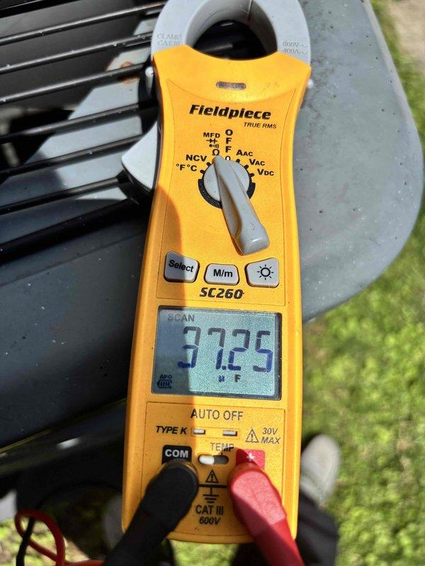 Responded to no-cooling complaint on 5-year-old system blowing warm air with thermostat set to 74°F but reading 79°F. Customer reported dampness near lineset with no ice buildup or tripped breakers. Upon inspection, utilized Fieldpiece SC260 clamp meter to diagnose electrical components and measure system amperage, which displayed 97.25 reading. Accessed outdoor condensing unit and inspected internal components including capacitor with multiple wire connections and CoreSense diagnostic module for Copeland compressor. Identified moisture concern at lineset location and verified proper electrical connections at capacitor terminals. Performed comprehensive system diagnostics to determine root cause of cooling loss and documented findings with photographic evidence of equipment condition and meter readings.