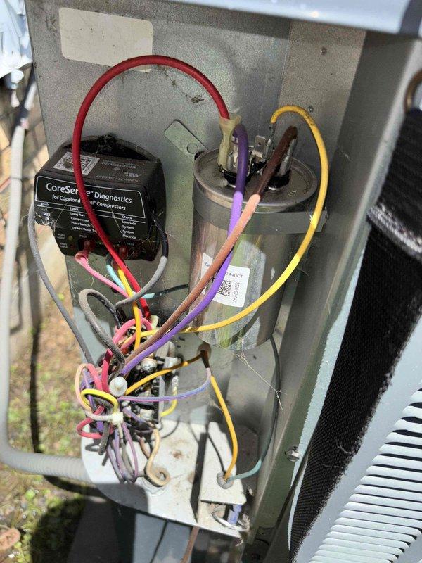 Responded to no-cooling complaint on 5-year-old system blowing warm air with thermostat set to 74°F but reading 79°F. Customer reported dampness near lineset with no ice buildup or tripped breakers. Upon inspection, utilized Fieldpiece SC260 clamp meter to diagnose electrical components and measure system amperage, which displayed 97.25 reading. Accessed outdoor condensing unit and inspected internal components including capacitor with multiple wire connections and CoreSense diagnostic module for Copeland compressor. Identified moisture concern at lineset location and verified proper electrical connections at capacitor terminals. Performed comprehensive system diagnostics to determine root cause of cooling loss and documented findings with photographic evidence of equipment condition and meter readings.