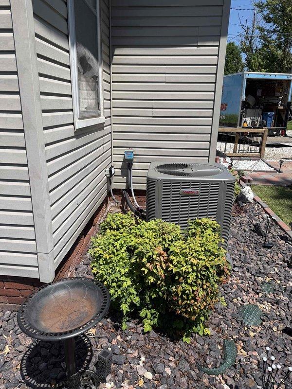Completed full HVAC system installation consisting of a 3.5-ton, 15.5 SEER air conditioning condenser unit and 97% AFUE furnace with blower assembly. The outdoor Lennox condenser was positioned on gravel bed against exterior siding with copper refrigerant lines properly routed and secured to the structure, while the indoor air handler was installed and verified operational with all components labeled and accessible for future service.