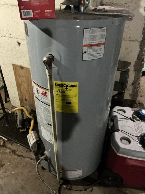 Performed USA Bronze tanked water heater maintenance service, which included a complete flush of the cylindrical gray residential water heater unit located in the basement utility area. Drained sediment buildup from the tank bottom, inspected all visible plumbing connections and fittings at the top of the unit, and verified proper operation of the temperature and pressure relief valve. All components were found to be functioning within normal parameters, and the unit was refilled and returned to service.
