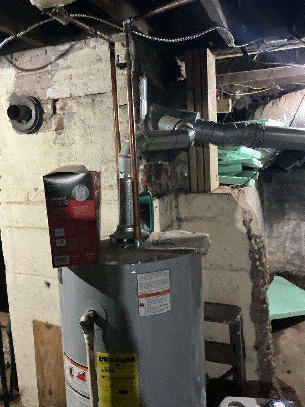 Performed USA Bronze tanked water heater maintenance service, which included a complete flush of the cylindrical gray residential water heater unit located in the basement utility area. Drained sediment buildup from the tank bottom, inspected all visible plumbing connections and fittings at the top of the unit, and verified proper operation of the temperature and pressure relief valve. All components were found to be functioning within normal parameters, and the unit was refilled and returned to service.