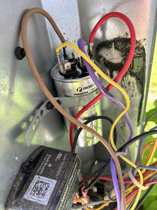 Responded to no-cooling call on 8-year-old residential HVAC system with warm air blowing from vents and non-operational outdoor unit condenser fan. Upon arrival, confirmed indoor airflow present but outdoor fan motor completely inoperative. Performed diagnostic evaluation of outdoor unit electrical components and identified failed dual-run capacitor with visible heat damage and burn marks on mounting panel. Capacitor tested at zero microfarads, well below manufacturer specifications, preventing both compressor and condenser fan motor from starting properly. Removed defective PROCER capacitor and replaced with new OEM-equivalent dual-run capacitor rated to system specifications. Cleaned electrical connections and mounting surface, removing carbon deposits from previous component failure. Verified all wire terminations secure at capacitor terminals and control board. Restored power to unit and confirmed compressor and condenser fan motor both operating within normal parameters. Checked a
