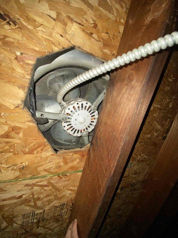 Responded to service call for attic ventilation fan producing abnormal noise that required the breaker to be shut off at night. Accessed attic space and inspected the gray exhaust fan unit mounted between roof rafters with flexible corrugated duct work. Evaluated fan motor assembly, housing, and electrical connections to identify source of rough operational sounds. Documented findings with photographs for insurance documentation purposes as requested.
