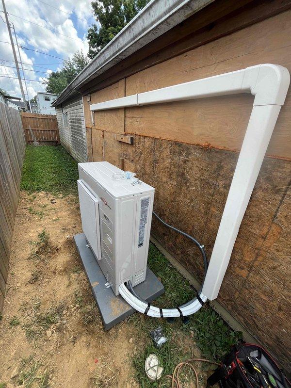 Completed installation of an 18,000 BTU ductless mini-split system in a residential property. Mounted outdoor condensing unit on concrete pad against exterior wood siding with proper refrigerant line sets and PVC condensate drain routing along the structure. Installed indoor air handler unit in attic space, securing it to structural joists with appropriate clearances for airflow and serviceability.