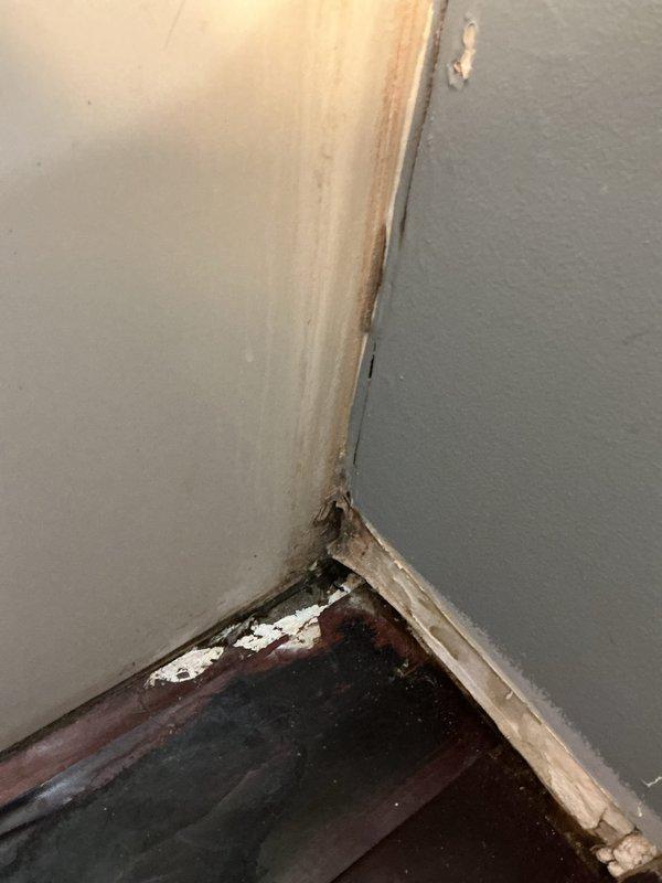 Responded to service call for assessment of suspected ongoing water leak and damage verification for insurance purposes. Upon arrival, conducted thorough inspection of upstairs bathroom and ceiling below. Identified significant water damage to ceiling drywall with bulging, soft spots, and compromised structural integrity requiring exploratory access hole for proper evaluation. Documented extensive deterioration including saturated ceiling material, water-stained walls with vertical streaking patterns, and severely damaged baseboard trim with warping, separation, and evidence of prolonged moisture exposure. Inspected bathroom floor adjacent to bathtub, confirming soft subflooring indicating potential continued leak from shower plumbing assembly. Previous repair work behind shower valve reportedly completed two years prior, however current damage pattern suggests either incomplete original repair or new leak source. Photographed all affected areas including compromised ceiling with acces