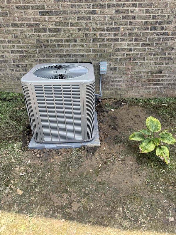 Completed installation of 4-ton, 17 SEER, 97% AFUE complete HVAC system at residential property. New outdoor condensing unit positioned on concrete pad against exterior brick wall with proper clearances maintained, electrical disconnect installed, and system commissioned with digital manifold gauges confirming proper refrigerant charge and operational parameters across all zones.