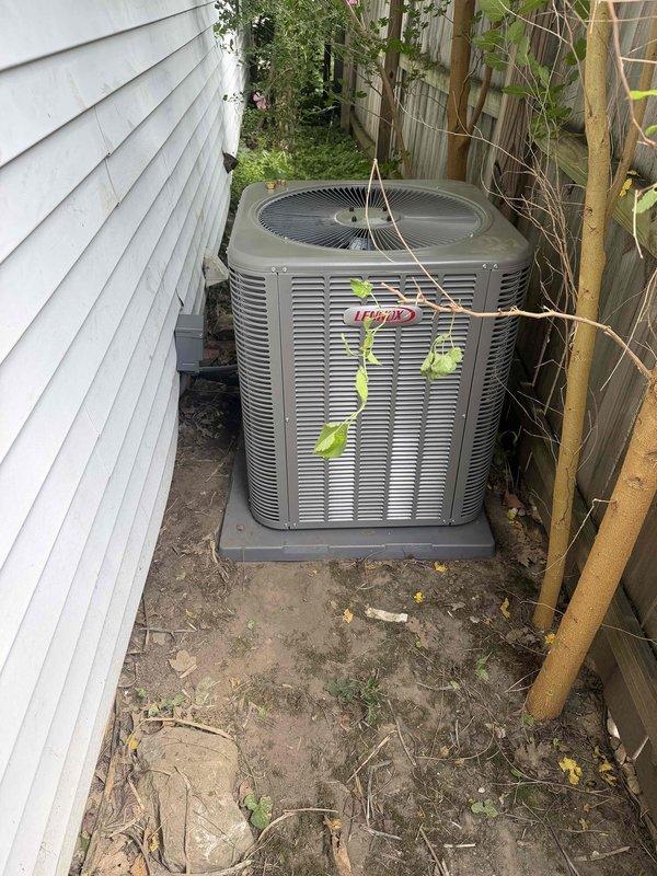 Completed installation of 3-ton, 14.7 SEER Lennox air conditioning system with matching evaporator coil in side yard location. Unit was properly positioned on concrete pad with adequate clearance, refrigerant lines were connected and charged to manufacturer specifications as verified by manifold gauge readings, and system was tested for proper operation with pressures stabilized at 439 PSIG high side and 310.8 PSIG low side with corresponding temperatures confirming correct refrigerant charge.