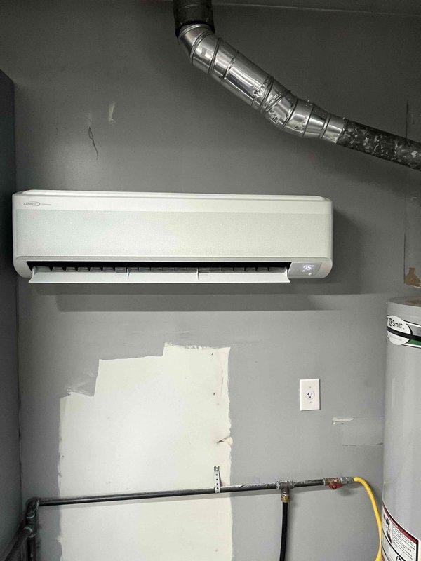 Completed installation of 24,000 BTU ductless mini-split system with single indoor head unit and outdoor Lennox condenser. Indoor evaporator mounted in interior mechanical room with refrigerant lines and electrical connections concealed through wall penetration; outdoor condensing unit positioned on composite pad against building exterior with proper clearances maintained. System tested and operational upon completion.