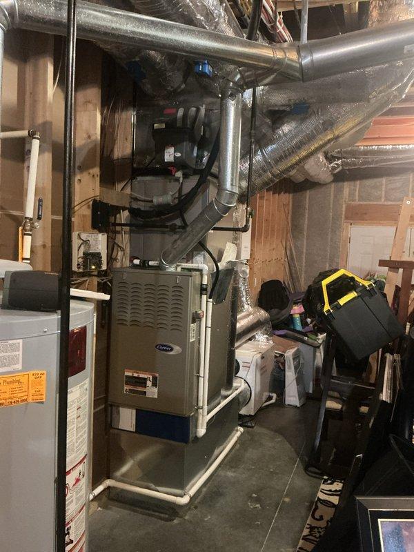 Responded to no cooling call on 15-year-old heat pump and air handler system with repeated breaker tripping issues. Upon arrival, indoor temperature was 84 degrees with no airflow from vents. Performed diagnostic inspection of Carrier furnace/air handler unit and associated electrical components in basement mechanical room. Identified electrical fault causing continuous circuit breaker trips, preventing system operation. Inspected ductwork, condensate drainage, and overall HVAC infrastructure for additional issues. Documented equipment condition and basement utility area configuration with photographic evidence showing air handler placement, ductwork routing, and mechanical room layout. System required electrical repair to restore cooling function and prevent further breaker trips.