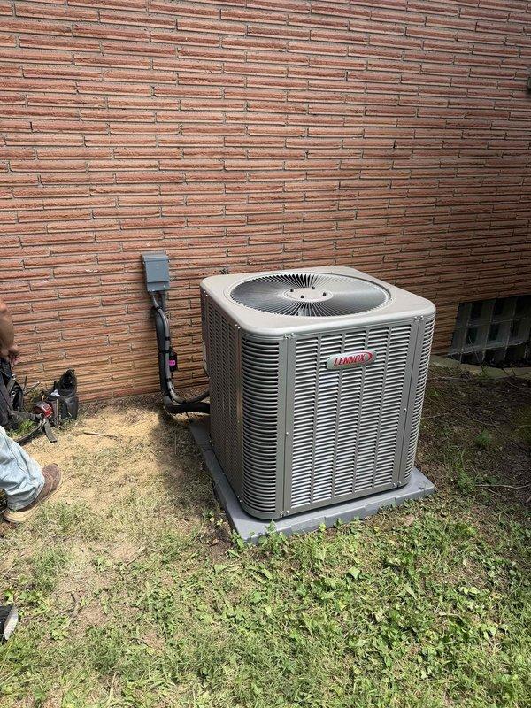 Completed full HVAC system installation featuring a 3-ton, 17 SEER Lennox air conditioning unit. The outdoor condenser was professionally mounted on a concrete pad against the building exterior with proper electrical disconnect box and conduit installation. System was charged with refrigerant, tested using calibrated diagnostic gauges, and verified to be operating within manufacturer specifications for temperature and pressure readings.