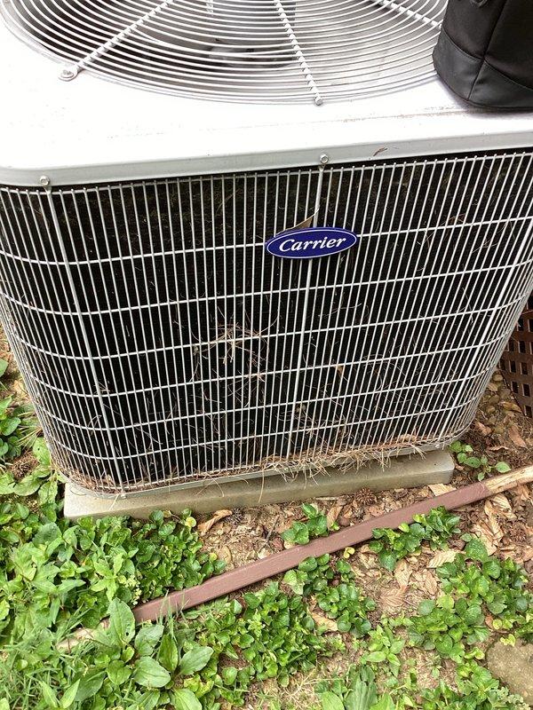 Responded to no-cool complaint on 11-year-old Carrier air conditioning system with inadequate cooling and warm airflow. Upon arrival, found outdoor condenser unit with heavily soiled top grille and significant debris accumulation including leaves, dirt, and organic matter restricting airflow. Condenser coils showed substantial contamination with dirt buildup on metal fins. Vegetation growth observed around unit base indicating lack of recent maintenance.

Performed complete system diagnostic including temperature differential measurements, refrigerant pressure checks, and airflow assessment. Confirmed system operational but running inefficiently due to restricted airflow at condenser unit. Thoroughly cleaned condenser coil fins using appropriate coil cleaner and low-pressure water rinse to remove dirt, debris, and biological growth. Cleared all leaf litter and organic material from top grille and surrounding unit perimeter. Removed vegetation growth from base of unit to ensure proper c