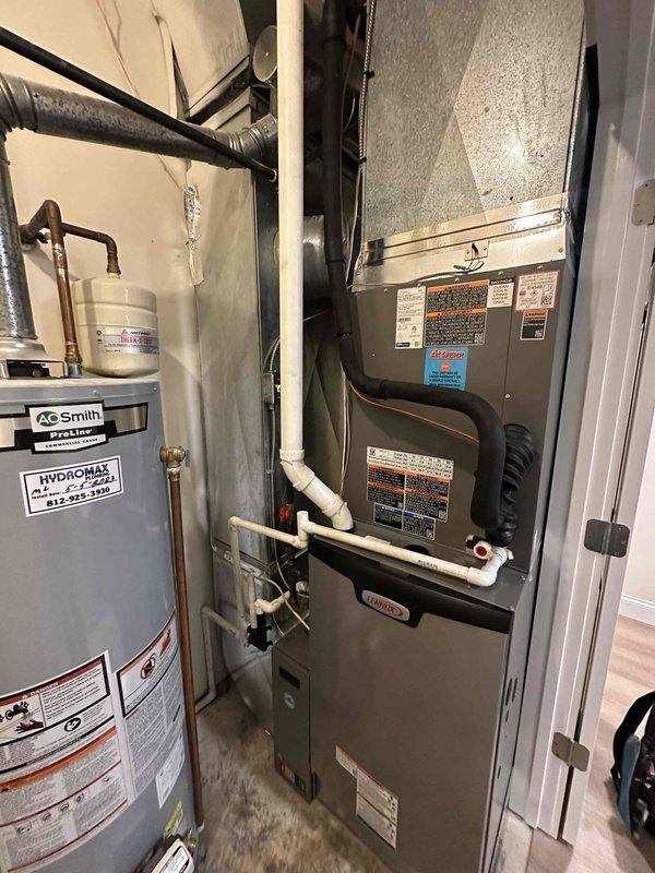 Completed full HVAC system installation including 4-ton, 18 SEER Lennox heat pump outdoor unit and matching indoor air handler with ProLine water heater integration. Installed outdoor condenser unit against exterior brick wall with proper clearance and positioning for optimal airflow and service access. Mounted indoor air handler in utility closet with complete ductwork connections utilizing black flexible duct transitions. Integrated white PVC condensate drain piping and venting system per manufacturer specifications. Connected all refrigerant lines between outdoor and indoor units with proper insulation and secure mounting. Installed and wired all electrical connections for both heating and cooling operations. Positioned and plumbed A.C. Smith ProLine water heater with copper supply lines, expansion tank, and appropriate safety devices. Verified all manufacturer labels, warning stickers, and technical specification plates properly displayed on equipment. Tested complete system operat