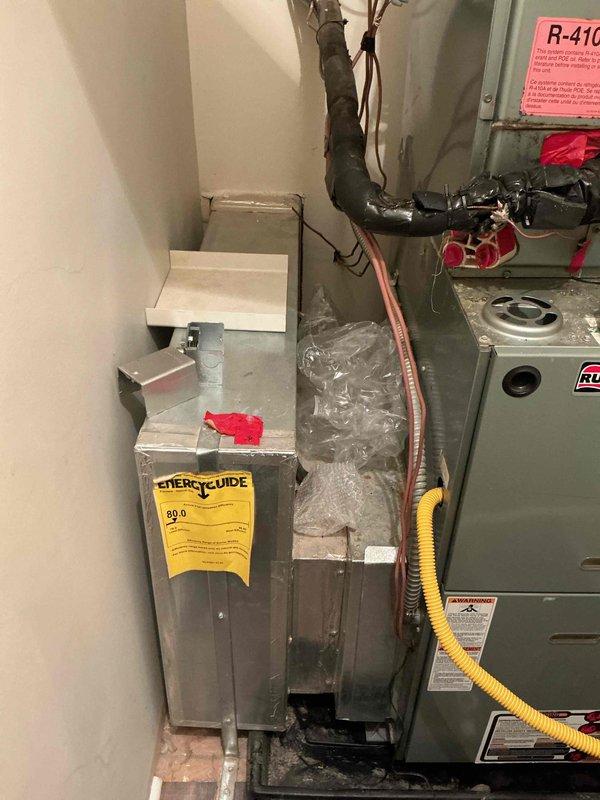 Conducted comprehensive assessment of existing HVAC system for replacement estimate. Documented current installation consisting of air handler unit and furnace system utilizing R-410A refrigerant in utility closet configuration. Evaluated equipment positioning, ductwork connections including flexible aluminum ducting at ceiling penetration, refrigerant line routing with black insulation, copper tubing connections, and yellow flexible gas line installation. Photographed electrical control board (HOM-300) and all mechanical components to provide accurate replacement specifications and system upgrade recommendations for Green A+ efficiency rating equipment.