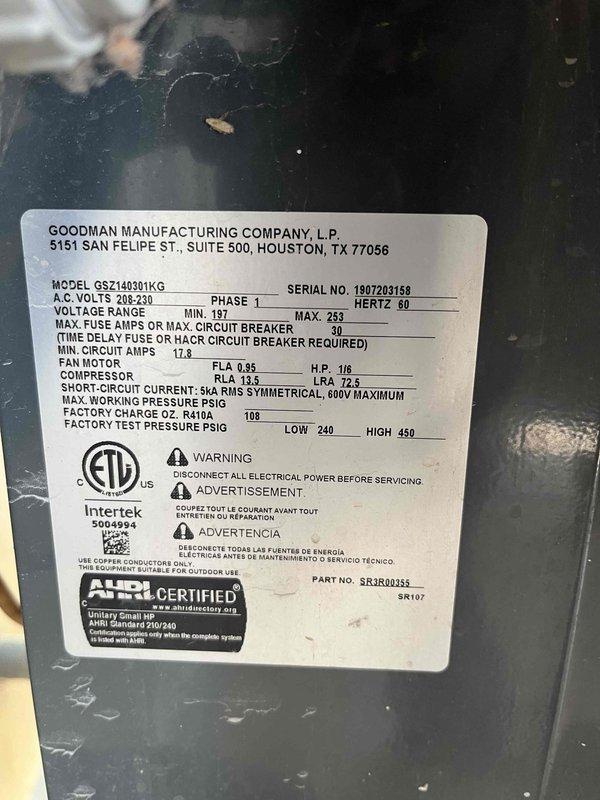 Responded to service call for AC not cooling properly with reported small leak. Documented existing Goodman split system equipment specifications including condenser unit model GSZ140301KG (serial 1907203158) rated at 208-230V, 1-phase operation. Photographed manufacturer data plate showing compressor and condenser fan motor specifications for reference. Assessed both air conditioning and furnace systems to provide comprehensive replacement estimate as requested. Captured documentation of existing equipment age and condition, including interior installation measurements and ductwork configuration.