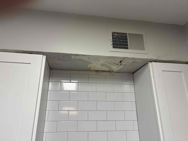 Responded to emergency water leak originating from HVAC ductwork in upstairs unit penetrating through ceiling into downstairs apartment. Upon arrival, found significant water damage with active condensation drip from supply duct causing ceiling deterioration, discoloration, and mold growth. Inspected HVAC system and confirmed duct insulation failure allowing condensate formation on cold supply line. Measured supply air temperature at 47°F, confirming proper cooling operation but inadequate vapor barrier on ductwork. Repaired compromised duct insulation, sealed all penetrations, and verified no further condensation occurring. Documented water-damaged ceiling areas requiring remediation by property maintenance.