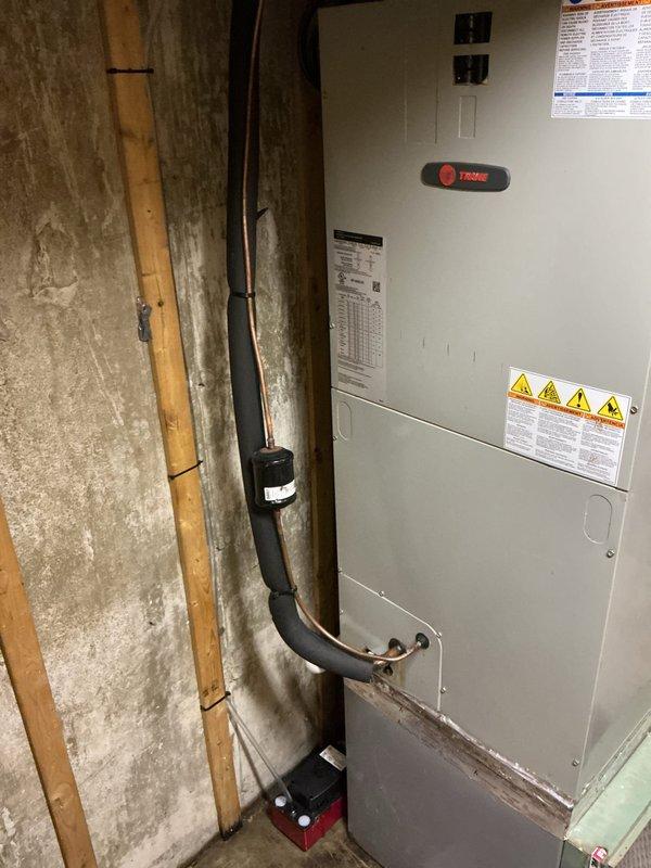 Responded to water leak call in basement area. Upon arrival, inspected Trane HVAC system and located source of leak at condensate pump assembly. Condensate pump was failing to properly discharge water, causing overflow from the unit. Examined condensate drainage system including PVC piping configuration and copper line connections. Verified condensate trap was functioning but pump mechanism required attention. Documented equipment condition with photographs showing unit installation, piping arrangement, and pump location at base of system. No water damage was observed to surrounding concrete floor or walls at time of inspection. Provided assessment of condensate pump failure and recommended repair options to restore proper drainage function and prevent future water accumulation.