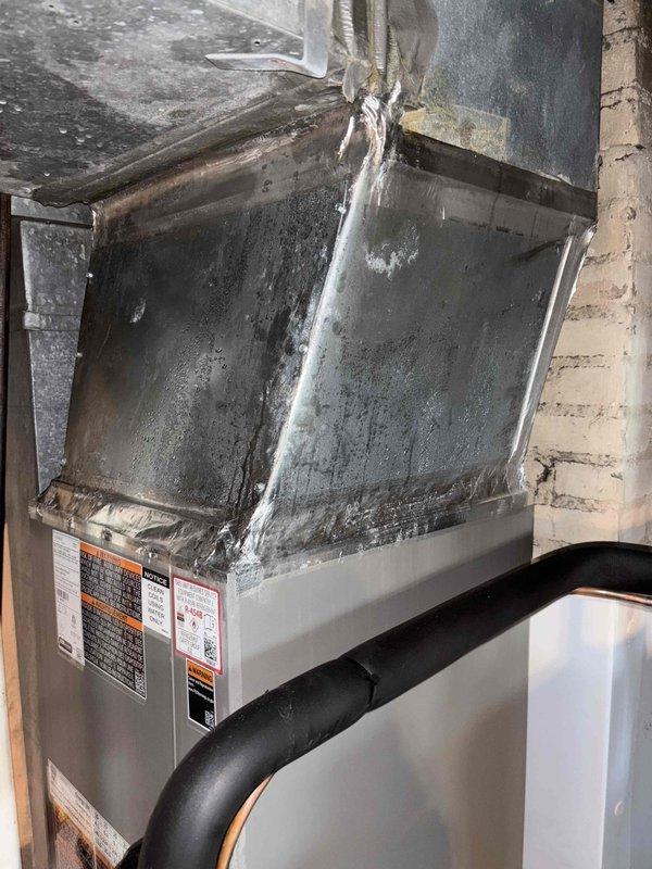 Responded to callback for recent HVAC installation experiencing condensation issues and steady dripping around furnace. Upon arrival, discovered severe ice and frost buildup on upper portion of air handler unit, indicating restricted airflow causing evaporator coil to freeze. Inspected condensate drainage system including PVC piping and confirmed proper installation but identified airflow restriction as root cause of excessive condensation. Verified system was operational at 73 degrees but running inefficiently due to frozen coil. Documented conditions with photos showing extensive frost accumulation on top panel and edges of unit. Addressed airflow issue, allowed coil to thaw, and verified proper condensate drainage through existing PVC system to resolve dripping concern.