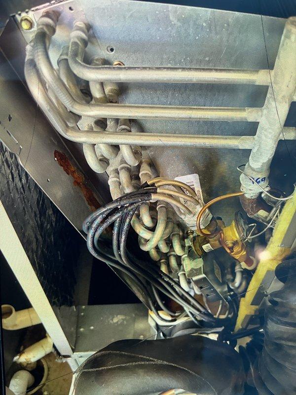 Responded to water leak complaint on one-year-old AC system. Upon inspection, identified condensation pooling on floor from recently installed unit. Examined evaporator coil assembly and drain system within cabinet. Verified system operational with normal heating and cooling functions. Inspected refrigerant lines, electrical connections, and insulation for proper installation. Documented internal components including evaporator coil configuration, wiring management, and insulation materials. System confirmed operational with no additional symptoms present.