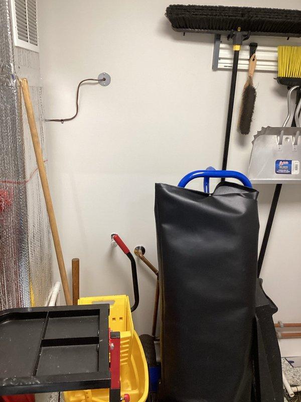 Responded to service call for tankless water heater not producing hot water. Performed diagnostic inspection of copper supply piping and connections in mechanical room area. Documented existing plumbing configuration including vertical copper lines with wall-mounted flanges and associated hydronic system components for follow-up assessment and repair recommendations.
