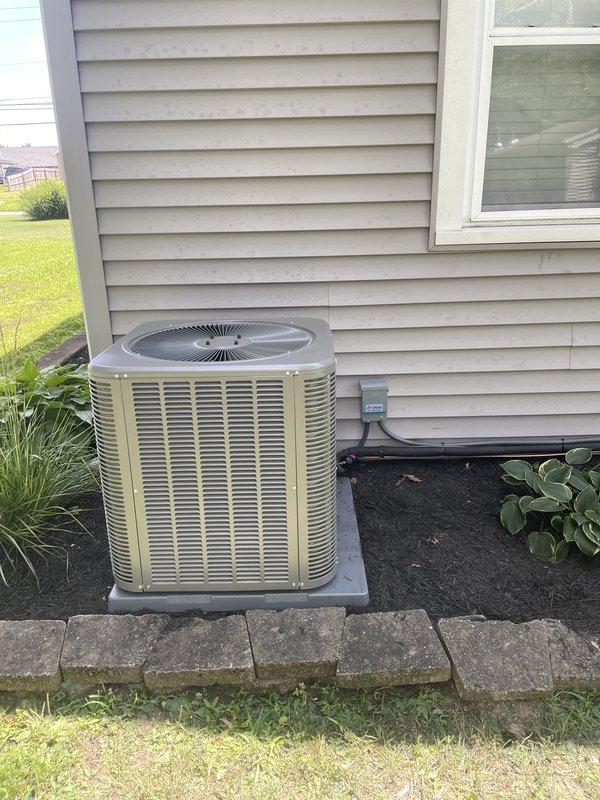 Completed installation of a 2.5 ton Lennox 15.5 SEER upflow air conditioning system with matching evaporator coil at residential property. The outdoor condensing unit was positioned on a concrete pad against the exterior wall with proper electrical disconnect installed, and the system was commissioned and verified operational.