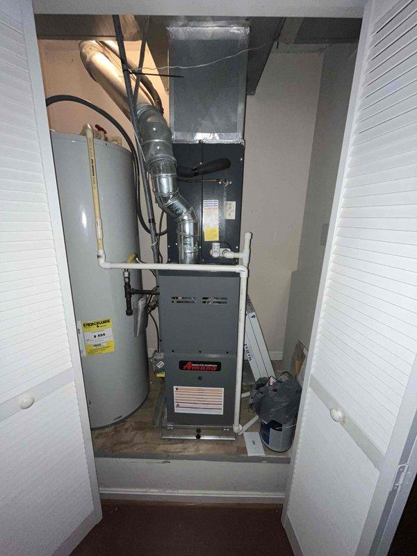 Completed comprehensive HVAC system replacement estimate for residential property featuring roof-mounted air conditioning condenser unit and indoor furnace installation. Assessed existing equipment configuration including outdoor condenser positioned on elevated wooden platform with weathered support structure on asphalt shingle roof, and indoor closet-mounted gas furnace with metallic ductwork and plenum connection. Evaluated complete system replacement requirements, documented equipment specifications, measured installation parameters, and provided homeowner with detailed replacement options for both outdoor condensing unit and indoor air handler/furnace system to ensure proper sizing and efficiency standards are met for whole-home comfort solution.