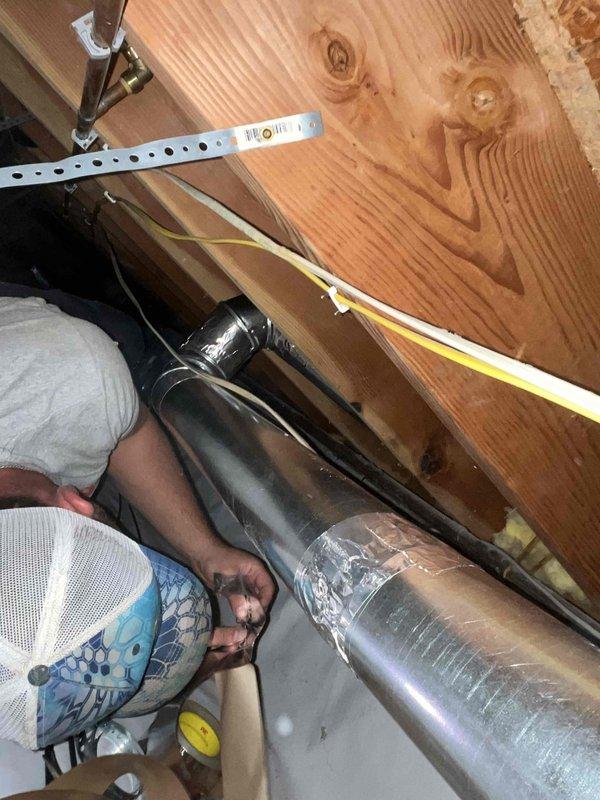Completed dryer vent replacement in residential attic space. Installed new metallic ductwork between floor joists, properly secured with metal clamps and hangers to wooden beams, and ensured proper routing through confined crawl space. All components were measured, fitted, and fastened according to code requirements for optimal airflow and safety.