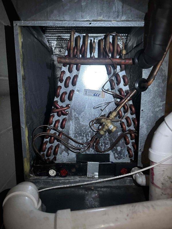 Completed routine planned maintenance on residential air conditioning system installed in 2020. Performed comprehensive AC tune-up including electrical diagnostics, measuring voltage at 385V using calibrated multimeter to verify proper power supply to system components. Inspected evaporator coil assembly, noting significant oxidation and patina on copper tubing consistent with system age and normal moisture exposure. Observed dust and debris accumulation on aluminum cooling fins. Verified refrigerant line connections and brass valve fittings for proper sealing. Checked condensate drain system including PVC piping for proper drainage. All electrical connections tested and found operational. System operating within normal parameters upon completion of maintenance service.