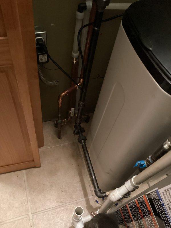 Completed installation of a 240V tankless water heater system with integrated 30-grain water softener in residential utility closet. Installation included proper copper piping connections, PVC drainage lines with blue-handled shut-off valves, electrical wiring with transformer mounting, and PVC vent pipe routed through ceiling to exterior. All components installed to code specifications with appropriate shut-off valves and access points for future maintenance.