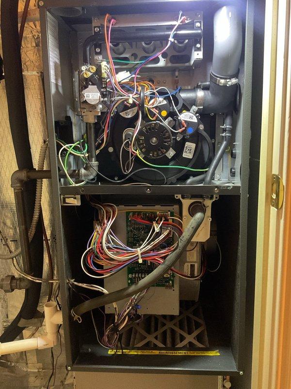 Completed scheduled planned duo maintenance on residential HVAC system including furnace and air conditioning components. Performed comprehensive inspection of all internal components with access panels removed, verified proper operation of blower motor assembly, examined control board and electrical connections for signs of wear or damage, and inspected heat exchanger condition. Checked all wire connections including multi-colored control wiring to circuit board and motor assembly, verified PVC condensate drain routing and secure mounting, and examined gas valve and mechanical fittings in lower compartment. Documented system condition through photographs showing internal components, wiring configurations, and overall unit integrity for maintenance records.