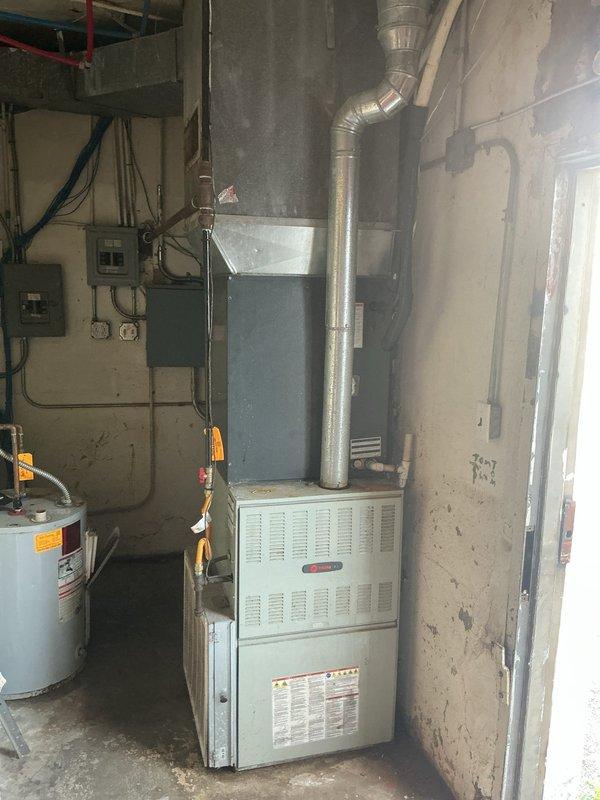 Responded to no-cooling call on property with two HVAC systems over 10 years old. Inspected rooftop condenser unit with non-operational outdoor fan and second system with reduced airflow performance. Evaluated both units for repair feasibility, documented equipment condition with photos showing rooftop installation and basement furnace/water heater setup. Provided system replacement options and water heater replacement quote as requested due to age and condition of existing equipment.