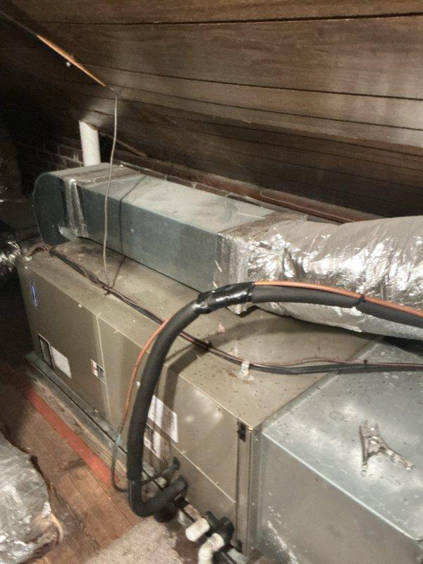 # Summary

Responded to no cooling complaint on 15-year-old residential HVAC system located in crawl space with air handler blowing but not producing cold air.

# Work Performed

Upon arrival, accessed air handling unit installed in confined crawl space area beneath residence. Unit appeared to be original equipment, approximately 15 years in service. Customer reported system was running and circulating air but failing to cool the living space.

Performed visual inspection of air handler and associated ductwork. Unit showed signs of age-appropriate wear with dusty conditions typical of crawl space installation. Verified blower operation - confirmed air handler was energized and moving air through the system as reported.

Inspected refrigerant line connections at air handler, noting black flexible refrigerant lines routing from unit. Examined condensate drain system with white PVC piping present and properly routed from unit base.

Assessed ductwork configuration including flexible silve