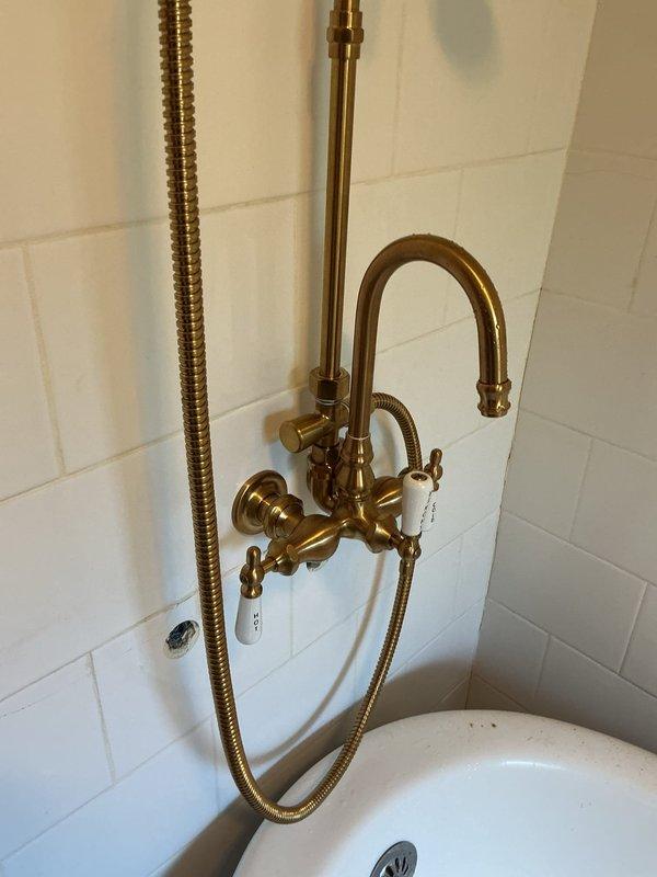 Completed inspection of vintage-style shower and tub installation on second floor, verifying proper mounting and functionality of ornate brass fixture assembly with cross-handle controls, curved spout, and flexible shower hose. Ran new water supply lines through wall cavity for washer and dryer hookup, routing plumbing from second floor location with appropriate drainage considerations. All installations tested for leaks and proper water pressure, with fixtures operating within normal parameters.