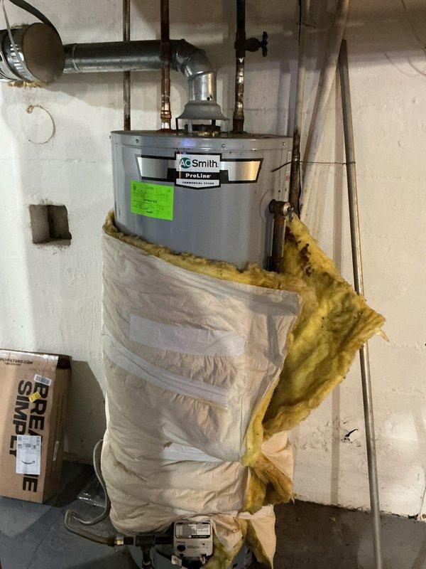 Responded to service call for leaking water heater of unknown age. Upon inspection, found A.O. Smith Proline water heater with active leak at base of unit, though unit was still operational and producing hot water. Assessed condition of tank, plumbing connections, and pressure relief valve assembly. Documented existing installation including copper supply lines, proper venting, and current insulation configuration around lower portion of tank. Provided customer with assessment findings and recommended replacement due to age-related tank deterioration and active leak condition.