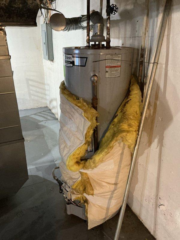 Responded to service call for leaking water heater of unknown age. Upon inspection, found A.O. Smith Proline water heater with active leak at base of unit, though unit was still operational and producing hot water. Assessed condition of tank, plumbing connections, and pressure relief valve assembly. Documented existing installation including copper supply lines, proper venting, and current insulation configuration around lower portion of tank. Provided customer with assessment findings and recommended replacement due to age-related tank deterioration and active leak condition.